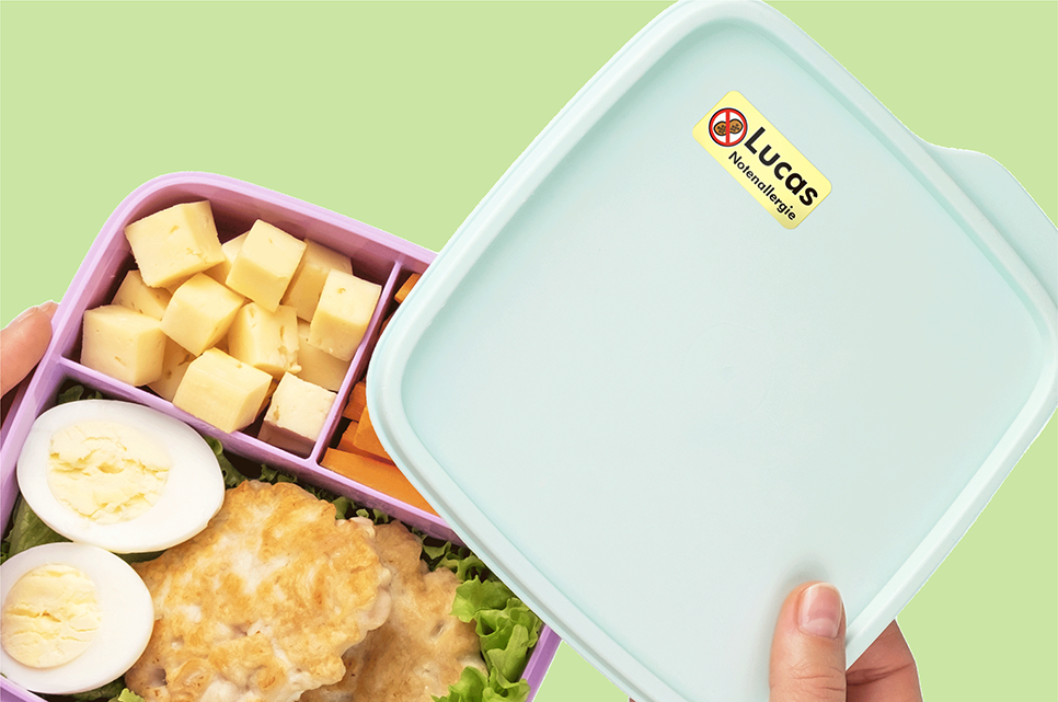 Boîte à tartines avec une étiquette d’allergie aux noix, ouverte pour montrer les aliments à l’intérieur